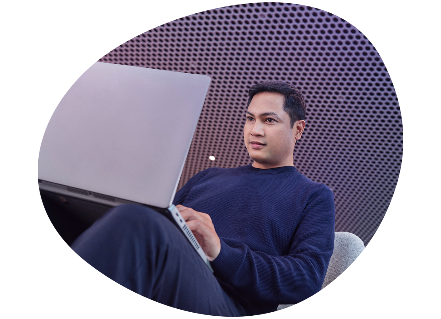 male EMD Serono employee working on a laptop, sitting in a lounge chair